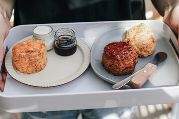 Delicious scones with Strawberry Jam, Clotted Cream and butter knife on a tray.