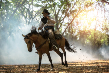 Fototapeta premium Cowboy riding a horse carrying a gun