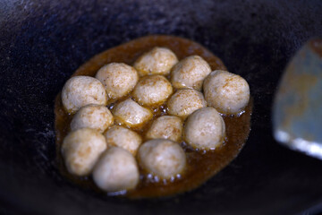 Fried chicken balls inside frying pan with palm cooking oil.