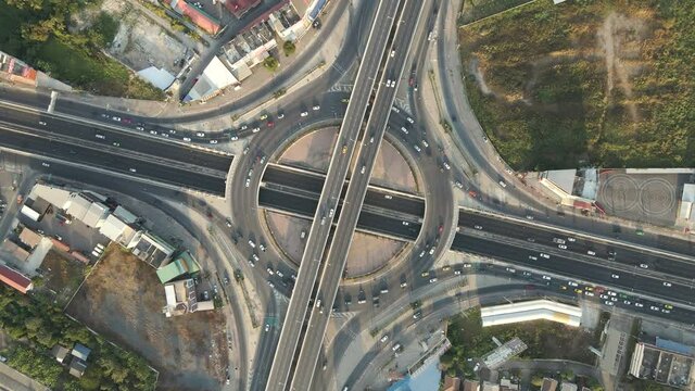 Aerial drone top-down angle with rotation shot of roundabout and crossing expressway with evening busy traffic.