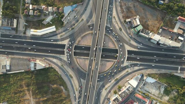 Aerial drone top-down angle shot of roundabout and crossing expressway with evening busy traffic.