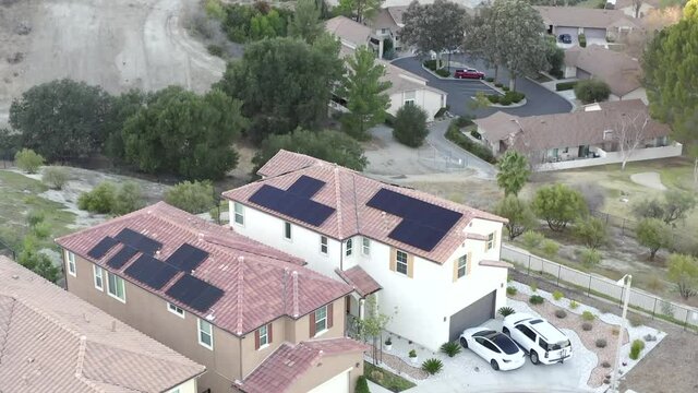 Two neighborhood houses with solar panels, renewable energy concept, Tesla Model 3 in driveway, aerial