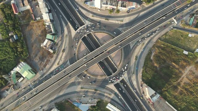 Slow rotated top-down aerial drone shot of roundabout and crossing expressway with evening busy traffic.