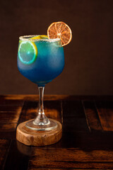 COCTEL AZUL EN UNA COPA CON NARANJA DESHIDRATADA
