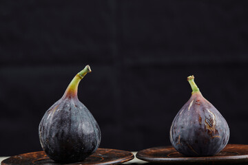 Two plates of figs on a dark background