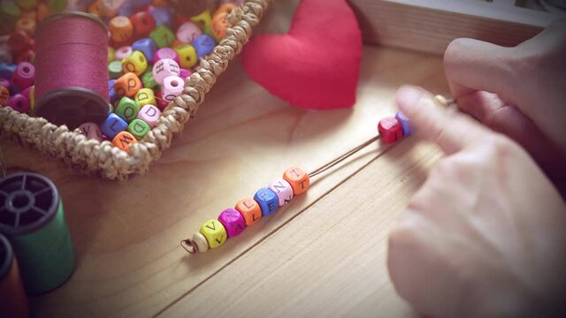 String a bracelet Wooden letter beads of VALENTINE word, Close up woman hand string with a colourful Wooden letter beads, VALENTINE concept. 