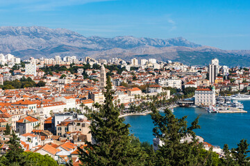 Fototapeta na wymiar The harbour, red roofs and mountains of Split, Croatia as seen from the cafe on Marjan Hill.