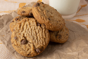 Vanilla cookies with chocolate tastes on rustic paper and accompanied by a glass of milk