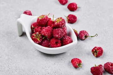 Fresh red raspberries in white bowl on white background