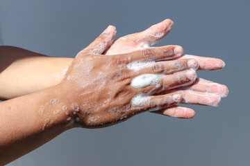 Fototapeta premium Man use soap and washing hands with grey background under the sunlight. Hygiene concept hand detail