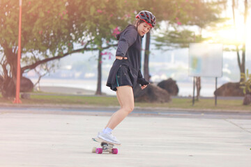 Asian women on skates board outdoors on beautiful summer day. Happy young women play surfskate at park on morning time. Sport activity lifestyle concept