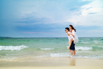 couple piggyback ride on the sea beach at Koh MunNork Island, Rayong, Thailand