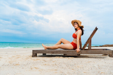 bikini woman sitting on a deck chair in the sea beach at Koh MunNork Island, Rayong, Thailand.