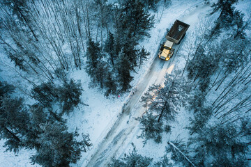 A rock truck makes it's way through  pathway in a dense Canadian boreal forest.
