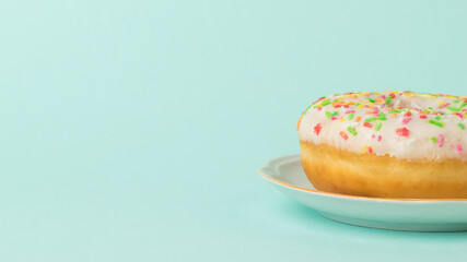 Fresh beautiful donut on a white plate on a light blue background.