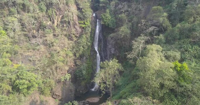 Flowing Streams Of Mainapi Waterfall In Cotigao Wildlife Sanctuary, Netravali Taluka Of South Goa, India. - Aerial Pullback Shot