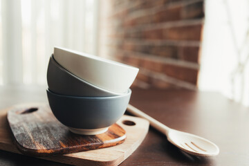Three ceramic bowls, wooden spoon on a wooden brown table. Blurred background
