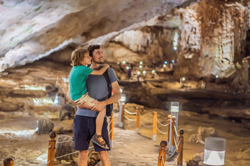 Dad and son tourists in Hang Sung Sot Grotto Cave of Surprises, Halong Bay, Vietnam. Traveling with children concept. Tourism after coronavirus