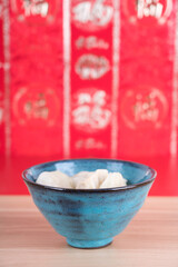 A bowl of dumplings in front of the red background