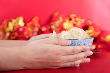 Hands holding a bowl of dumplings on a red background