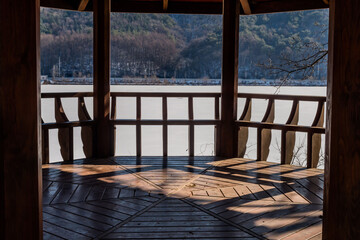 View inside covered pavilion beside frozen lake.