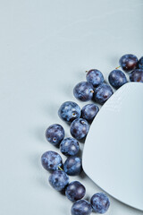 Group of fresh plums around the white plate