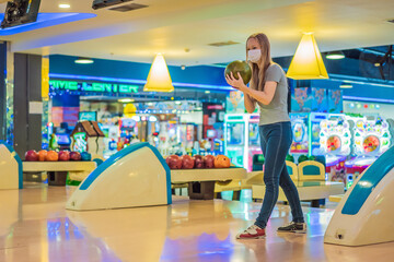 Woman playing bowling with medical masks during COVID-19 coronavirus in bowling club