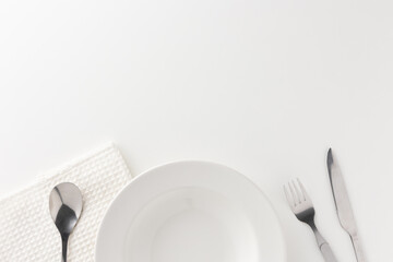 White empty plates set on the table with knives and forks and tablecloths. Ready to eat