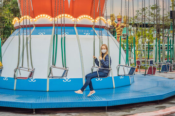 Woman riding a carousel wearing a medical mask during COVID-19 coronavirus