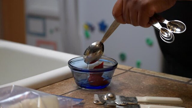 Adding a tablespoon of vinegar to tomato paste for a homemade recipe - African American hand in view