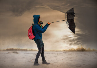 A woman tries to hold onto her umbrella during a strong storm. Impending storm clouds are looming...