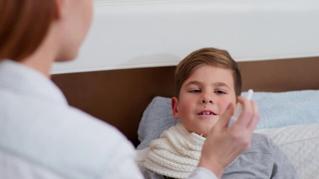 Caring Female Parent Examines Condition Of His Sick Son And Drips His Nose From Runny Nose During Virus And Infection