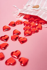 selective focus. Valentine's day card. glass red hearts scattered from a beautiful cloth bag. the view from the top. pink background