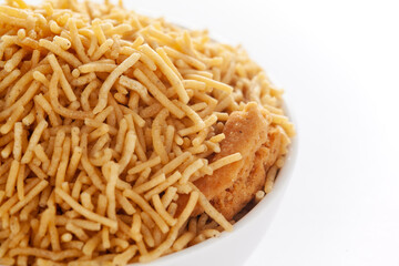 Indian spicy snacks (Namkeen) - Bikaneri Besan Bhujia in a white bowl, made with chickpea flour (Besan), side view, against the white background.