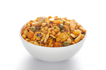 Pile of Indian spicy snacks (Namkeen) - 'All in one' in a white bowl, made with fried peanut, corn flakes, sweet pea, pulses, cashew nuts, etc. side view, against the white background.
