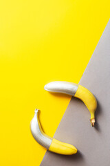 Painted silver color bananas on a yellow-gray background. Minimalistic abstract food image	