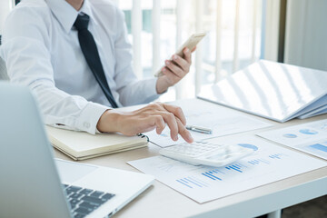 The businessman hand sits at their desks and calculates financial graphs showing the results of their investments planning the process of successful business growth