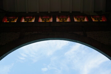 Curved walls and white clouds against a blue sky.