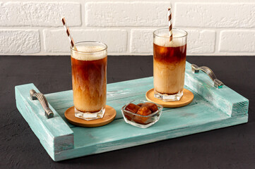 Ice coffee on a woodtray with cream being poured into it showing the texture and refreshing look of the drink