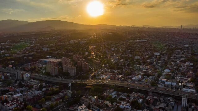 Aerial drone lapse view of dramatic sunset over a highway and the cityscape, in Mexico city, - lateral, tracking, hyperlapse shot