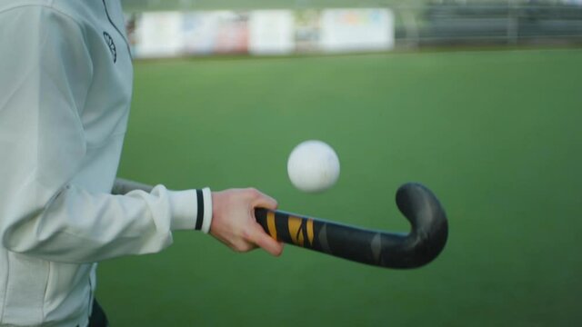 Slow motion of field hockey player bouncing white ball on side of stick