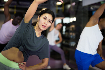 Fototapeta na wymiar Portrait of sporty woman doing cardio exercises training with step platform at fitness center