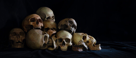 The pile of old skulls put on black cloth and black background
