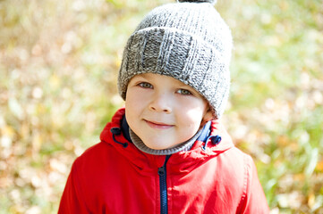 Cute boy in a red jacket and a warm knitted hat.