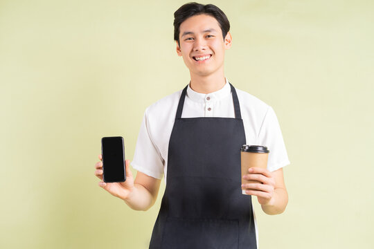 Asian waitress holding a phone and a paper cup in one hand is smiling