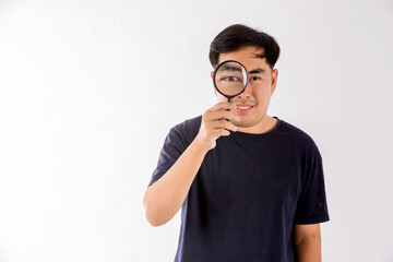Man holding magnifying glass on white background. man with a magnifying glass in studio. Positive curious man in casual wear looking at through magnifier 