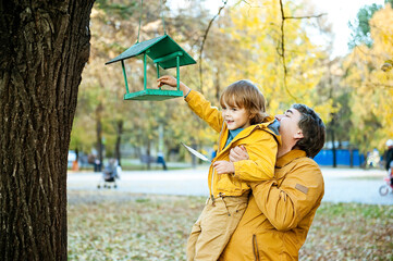 Father and son feed the birds in the city Park.