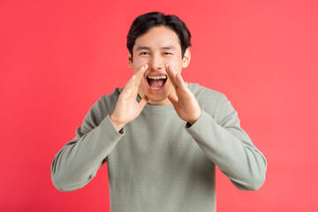 A photo of a handsome Asian man covering his mouth with his hands screamed in joy