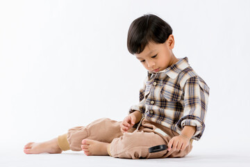 Child holding magnifying glass on white background. Boy with a magnifying glass in studio. Positive curious boy in casual wear looking at through magnifier 