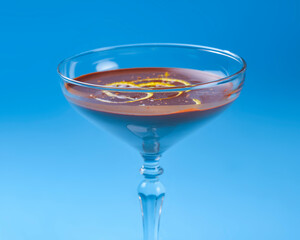Chocolate cocktail with lemon slices in tall glass over pastel blue background.